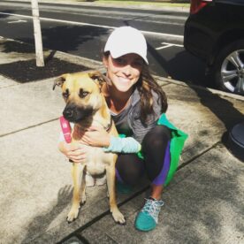 Smiling young woman crouching and hugging dog